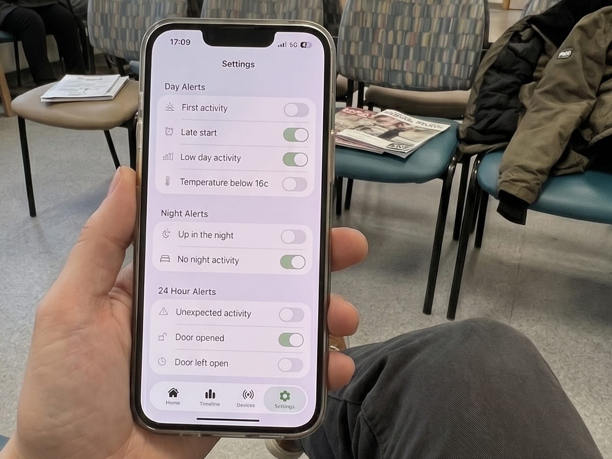 Someone in a waiting room checking the Howz app settings, where day, night and 24-hour alerts can be switched on or off