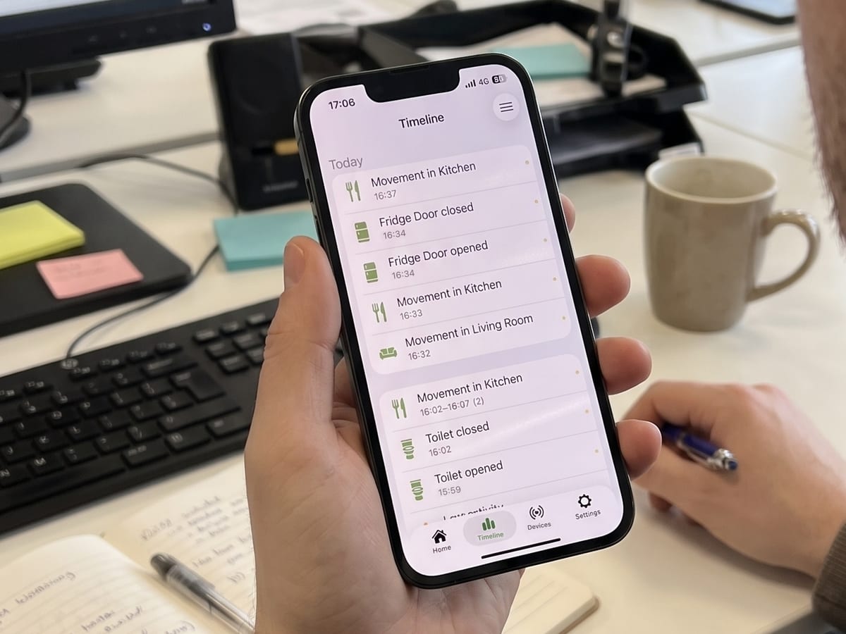 Someone at an office desk checking the Howz app timeline, which lists today’s events such as movement in the kitchen and the fridge door opening