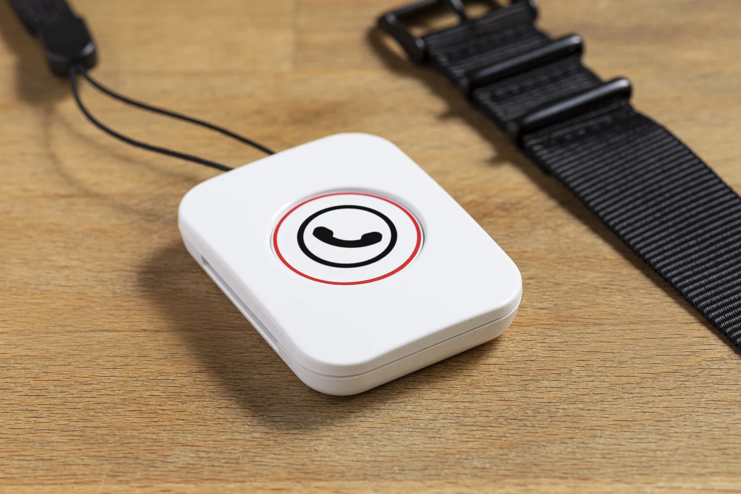 The Howz button on a wooden table next to a watch strap